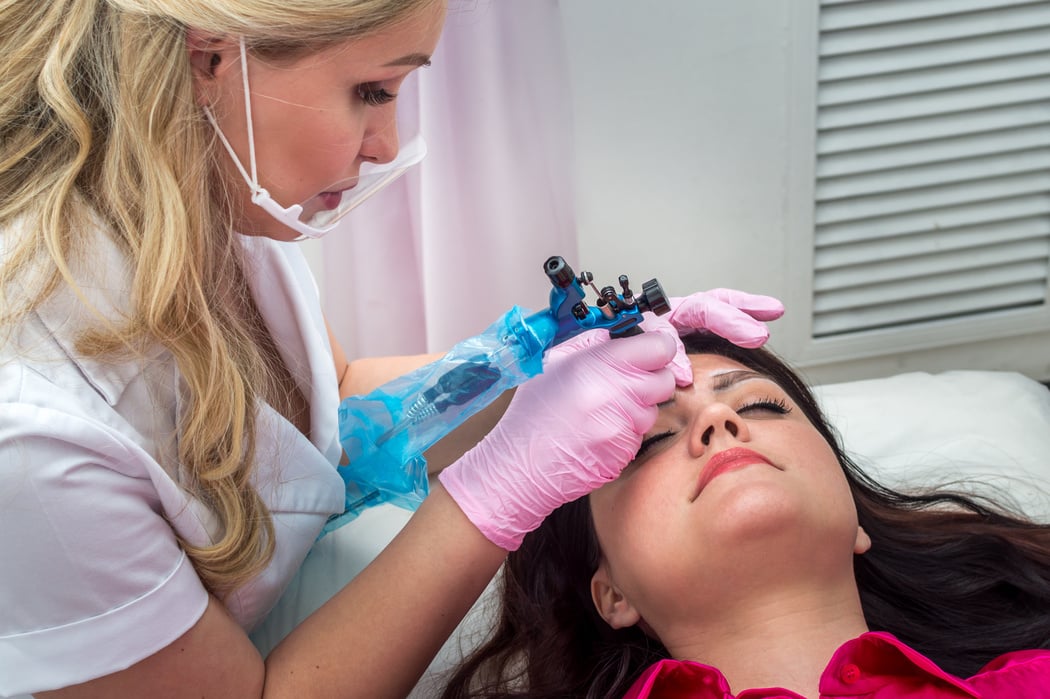 Young Woman Doing Eyebrow Microblading in a Beauty Salon with a Permanent Make-up Master